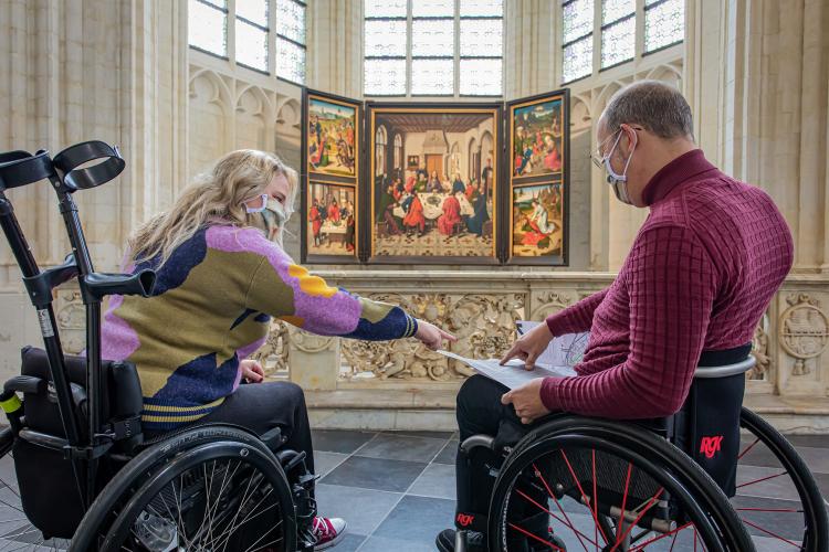 twee personen in rolstoel voor schilderij