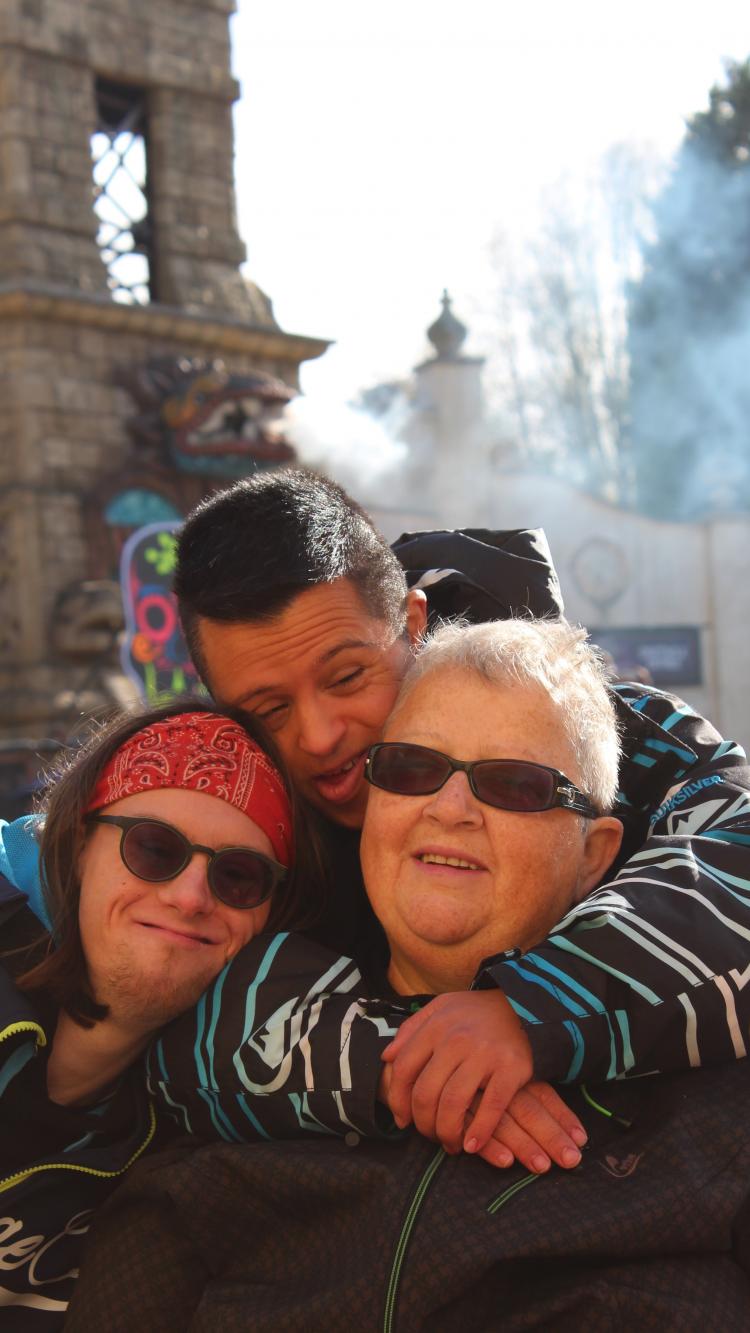 mama met twee volwassen zonen met syndroom van Down die haar omhelzen