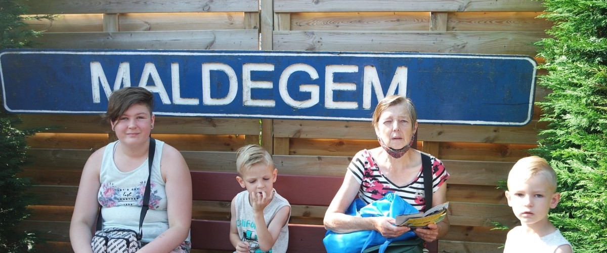 oma met meisje en twee jongens voor woord Maldegem op bankje