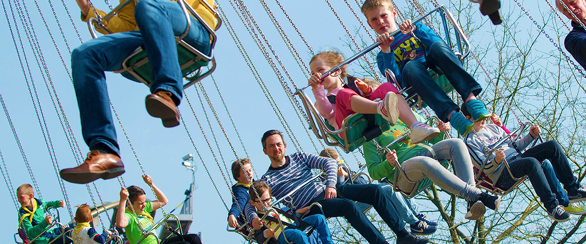 mensen op attractie van vliegende carrousel (stoeltjes aan kettingen die ronddraaien)